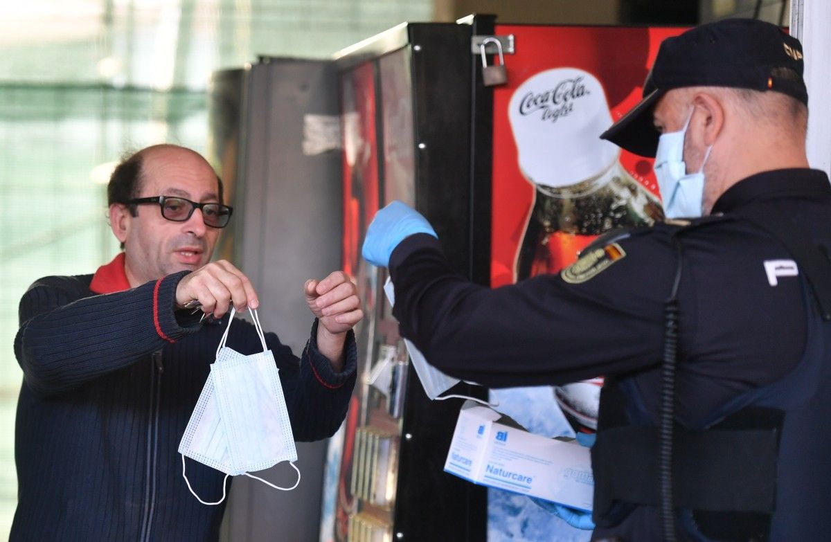 Un agente de Policía reparte mascarillas entre los usuarios del transporte público