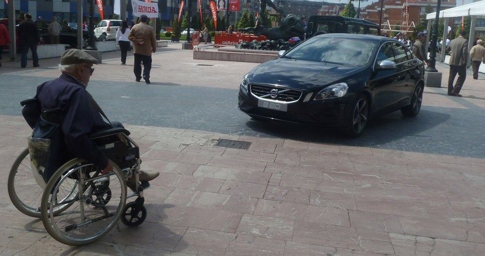 Una persona en silla de ruedas se acerca a un coche aparcado