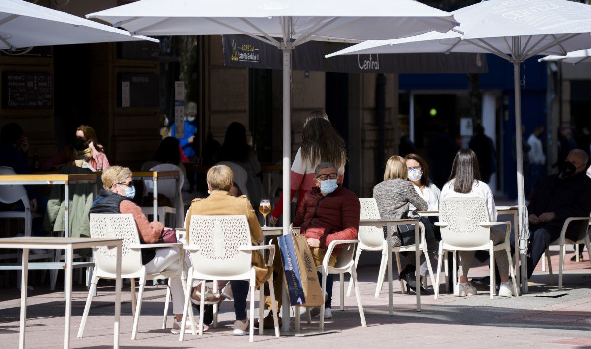 Personas en la terraza de una bar con mascarilla