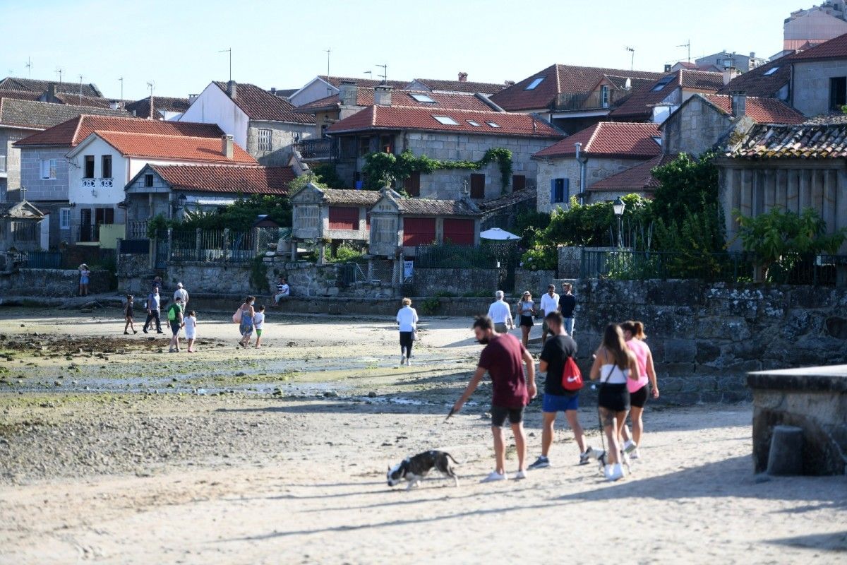 Personas paseando por la playa de O Padrón, en Combarro