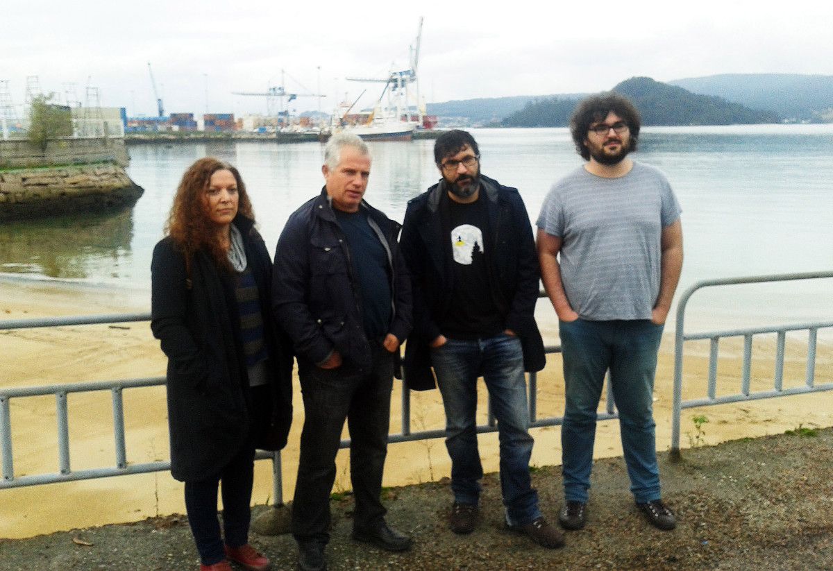 Integrantes de AGE visitan Os Pracres, con los rellenos del Puerto de Marín al fondo