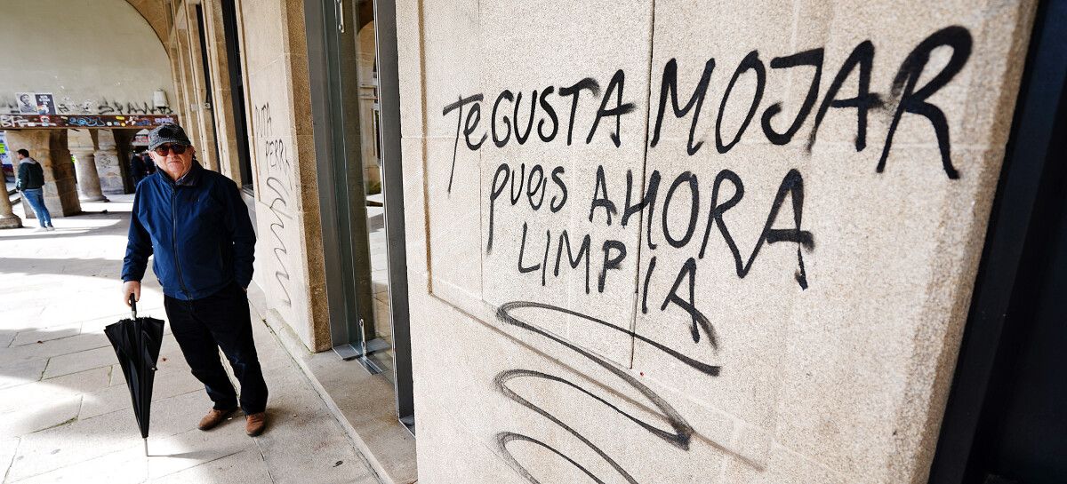 Pintadas en la fachada del nº 8 de la plaza de A Ferrería ante la mirada de un vecino