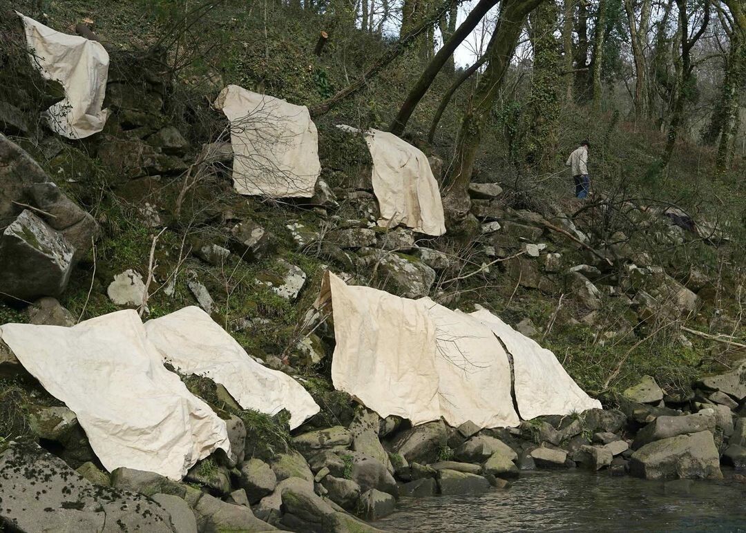 Soaking and drying canvas on the banks of the river Lérez, de Simon Callery