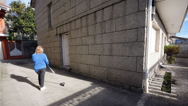 Encarnación limpia el patio delante de la puerta lateral de la vivienda por la que entraron los vecinos para desalojarlossmente unha casa en Combarro