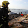 Tarefas de extinción do incendio no catamarán 'Boramar', totalmente calcinado e embarrancado na Toxa