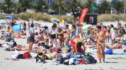 Gente paseando y tomando sol en la playa en Sanxenxo